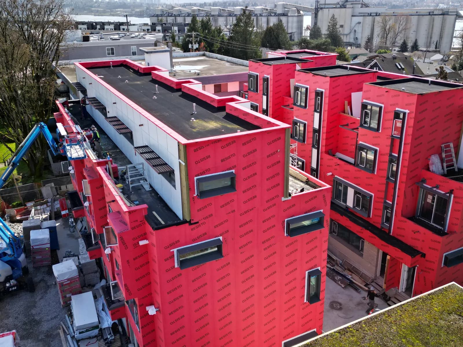 Multi-family building mid-construction with red Typar building envelope wrap — BC restoration project