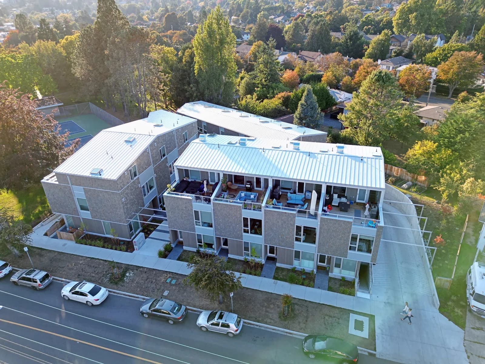 Grey-clad multi-family rental building with rooftop terraces on a BC suburban street, an MV Construction renovation project