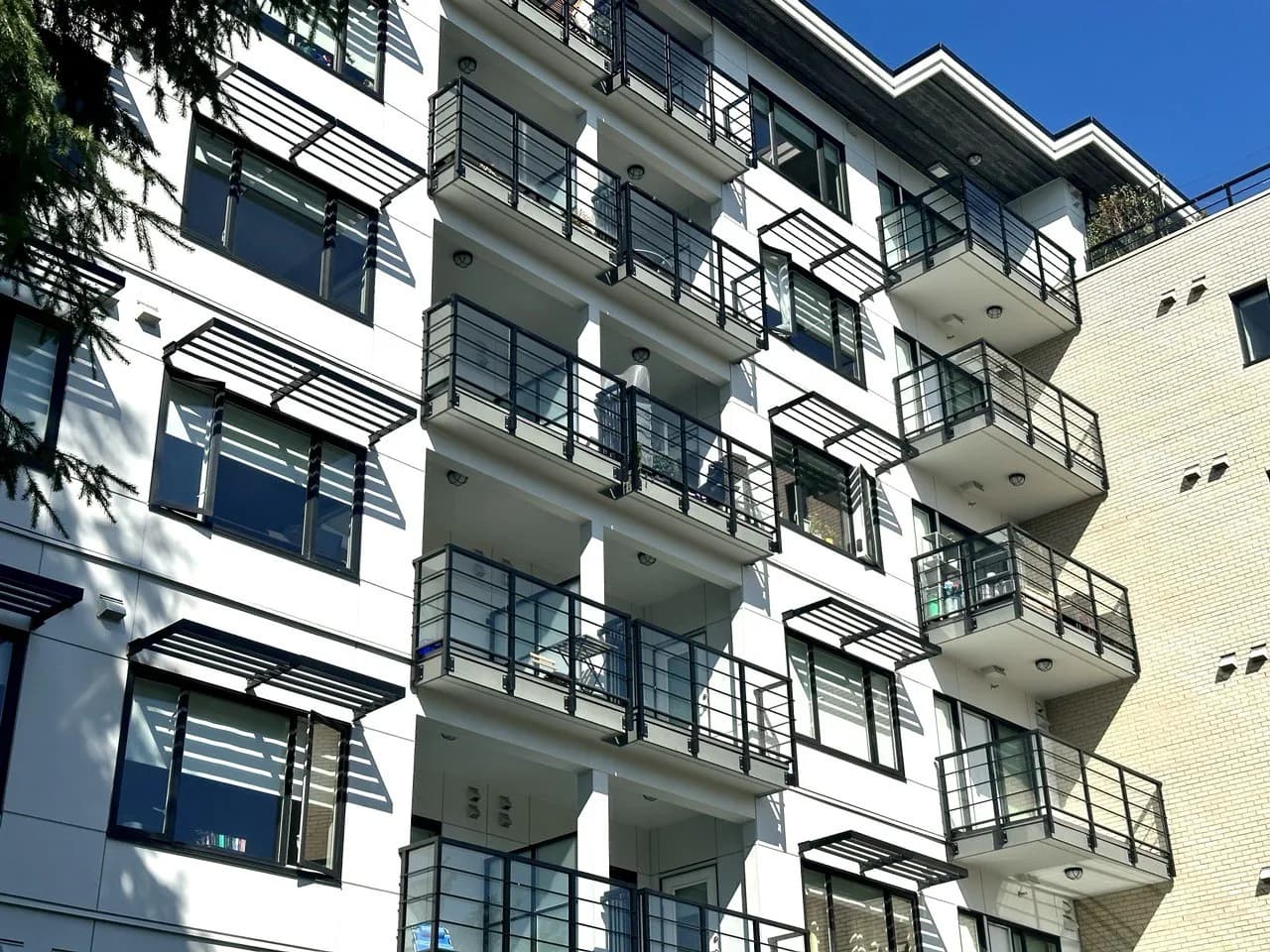 Multi-family building with steel balcony railings, BC — balcony membrane repair context