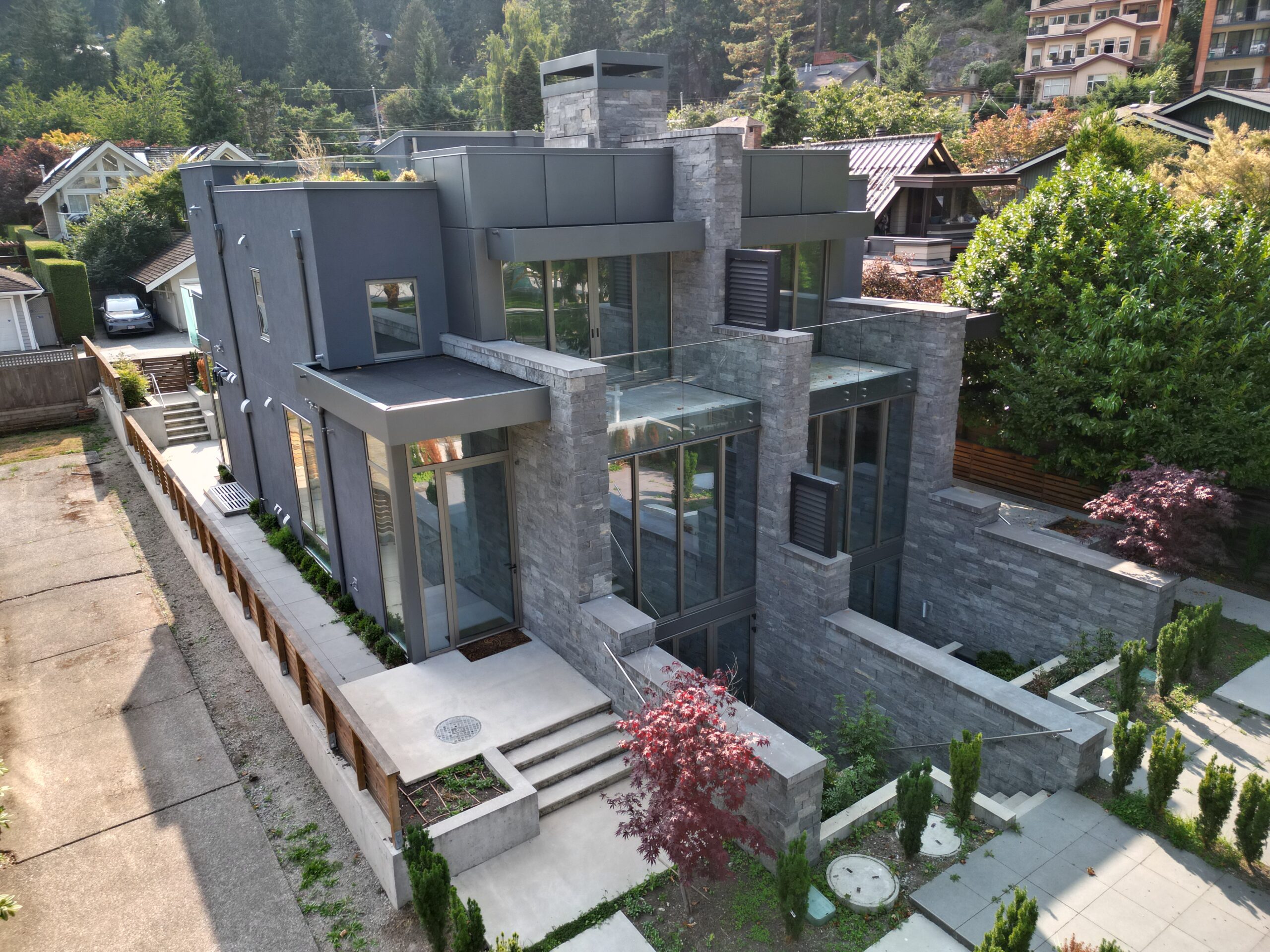 Modern waterfront BC home with real stone facade and full-height glass, cultured stone vs real stone comparison